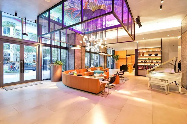 a room with lots of white furniture a rug and a potted plant