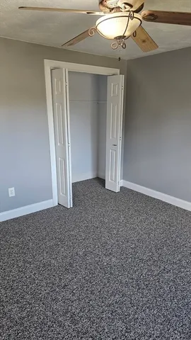 an empty room with a ceiling fan and carpet