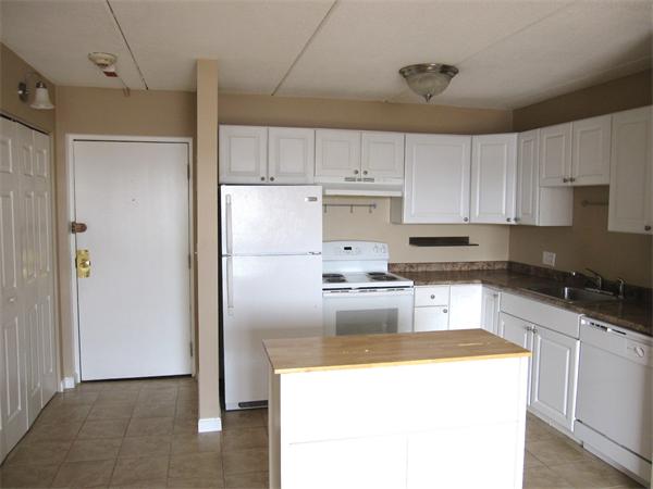 46 Cochituate Road, Unit 203 Framingham, MA 01701 - Photo 2 of 5 a kitchen with granite countertop a refrigerator a sink a stove and white cabinets