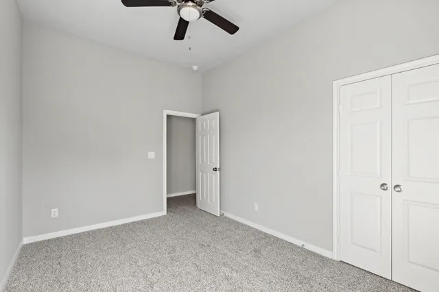 an empty room with a ceiling fan and carpet