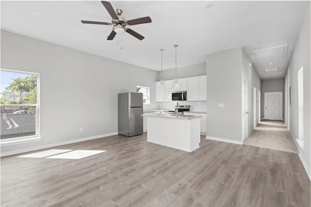 a view of kitchen with stainless steel appliances kitchen island hardwood floor and window
