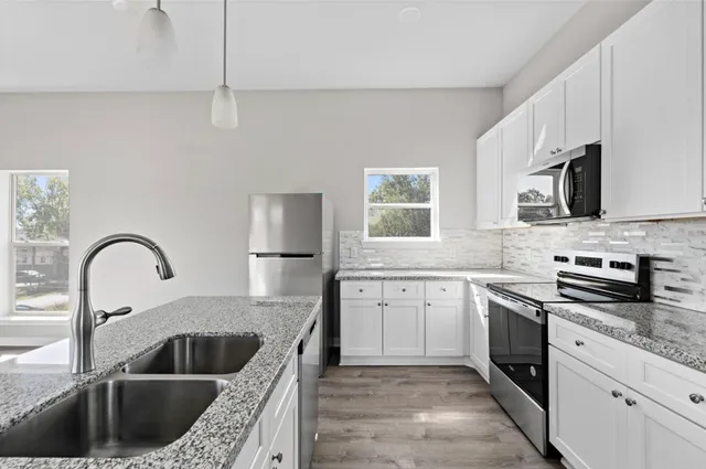a kitchen with stainless steel appliances granite countertop a sink a stove and a refrigerator