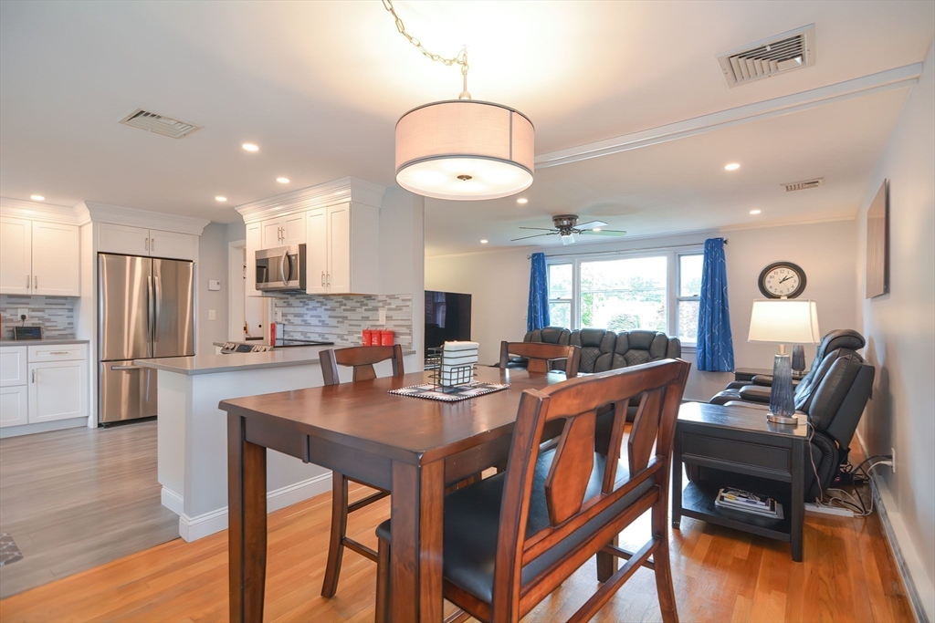 123 Capper Drive Canton, MA 02021 - Photo 10 of 32 a kitchen with stainless steel appliances kitchen island granite countertop a stove a refrigerator a kitchen island a dining table and chairs with wooden floor