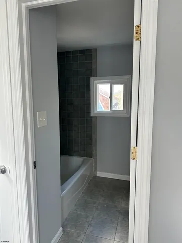 a view of an empty room with wooden floor and a ceiling fan