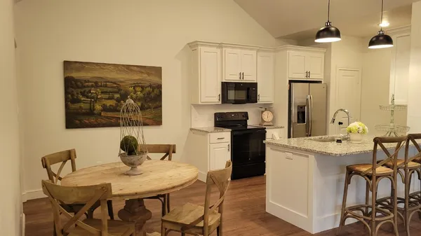 a kitchen with stainless steel appliances kitchen island granite countertop a table chairs and a refrigerator