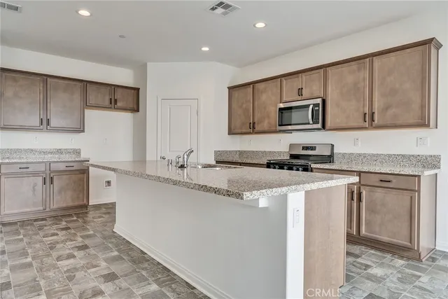 a kitchen with stainless steel appliances granite countertop a stove a sink and a microwave