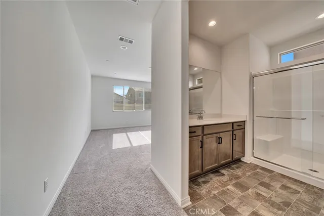 a view of a hallway to an empty room with cabinet and a window