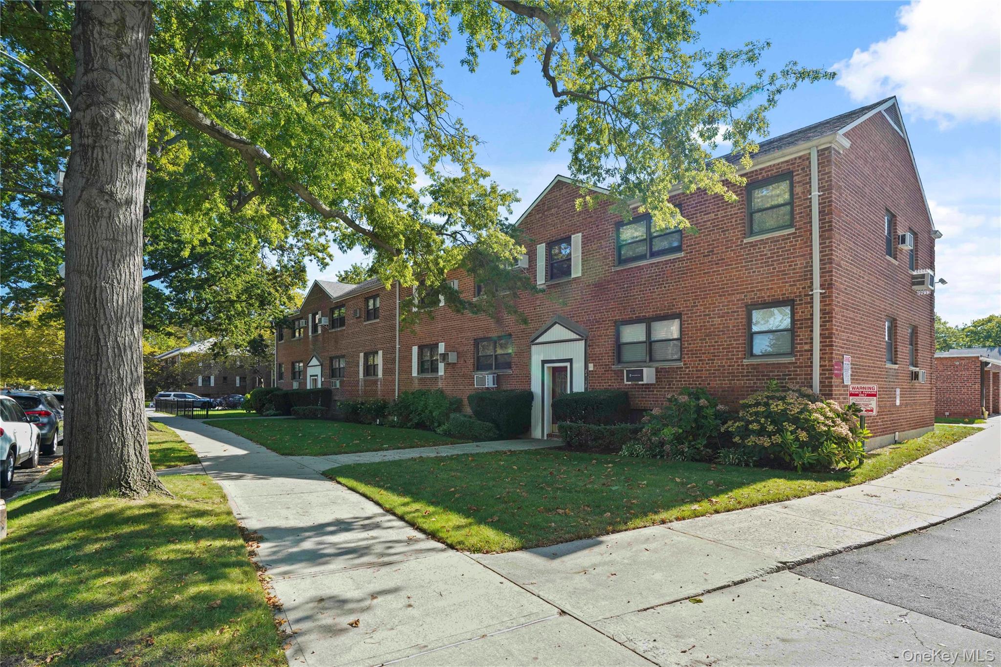 84-18 155th Avenue, Unit 1R Queens, NY 11414 - Photo 21 of 26 a view of a brick house with a yard and large trees