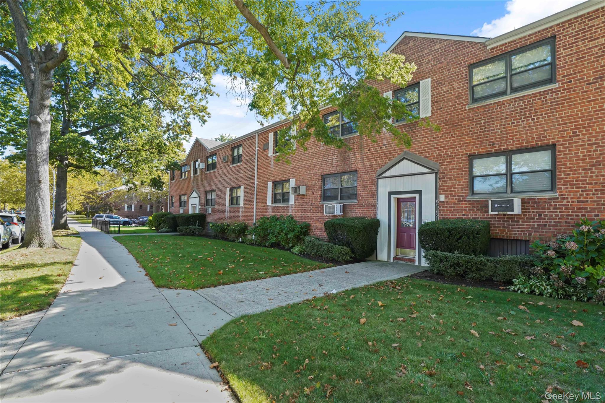 84-18 155th Avenue, Unit 1R Queens, NY 11414 - Photo 25 of 26 a front view of a house with a yard and trees