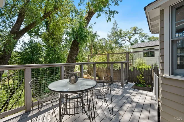 a balcony with a table and chairs and wooden fence