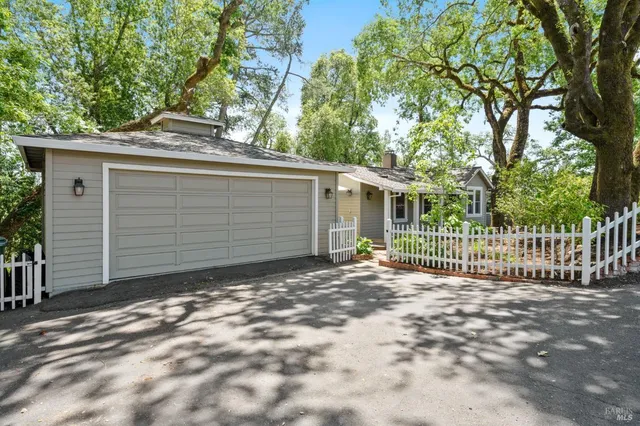 a view of a house with a small yard and a large tree