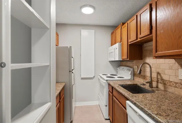 a kitchen with granite countertop a sink stove and refrigerator