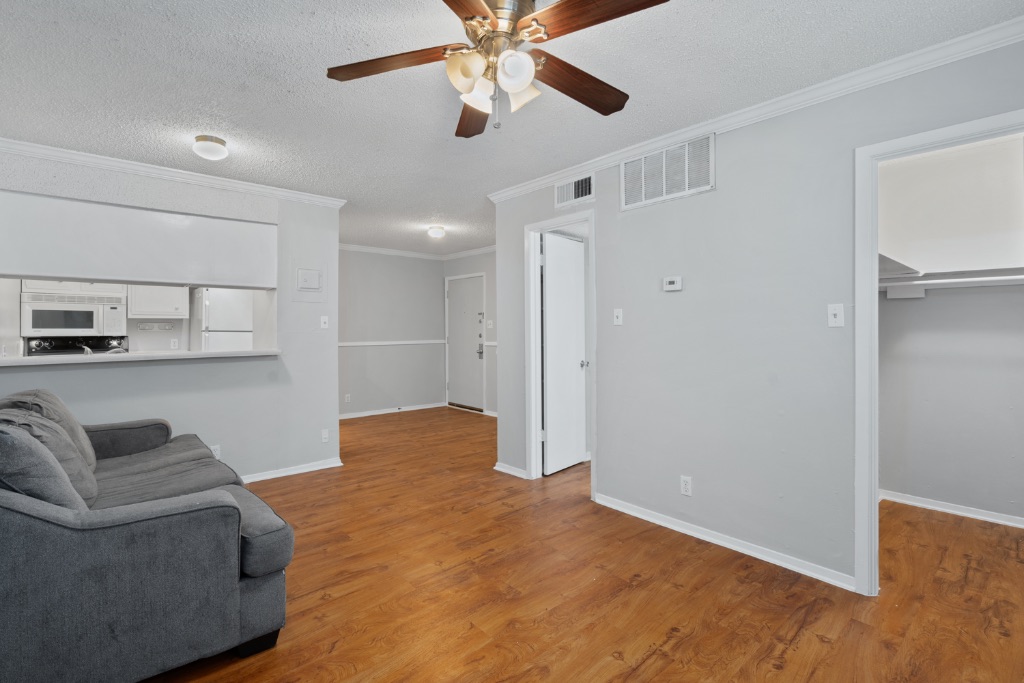 4103 Speedway, Unit 105 Austin, TX 78751 - Photo 1 of 10 Living area with a textured ceiling, ornamental molding, wood finished floors, and a ceiling fan