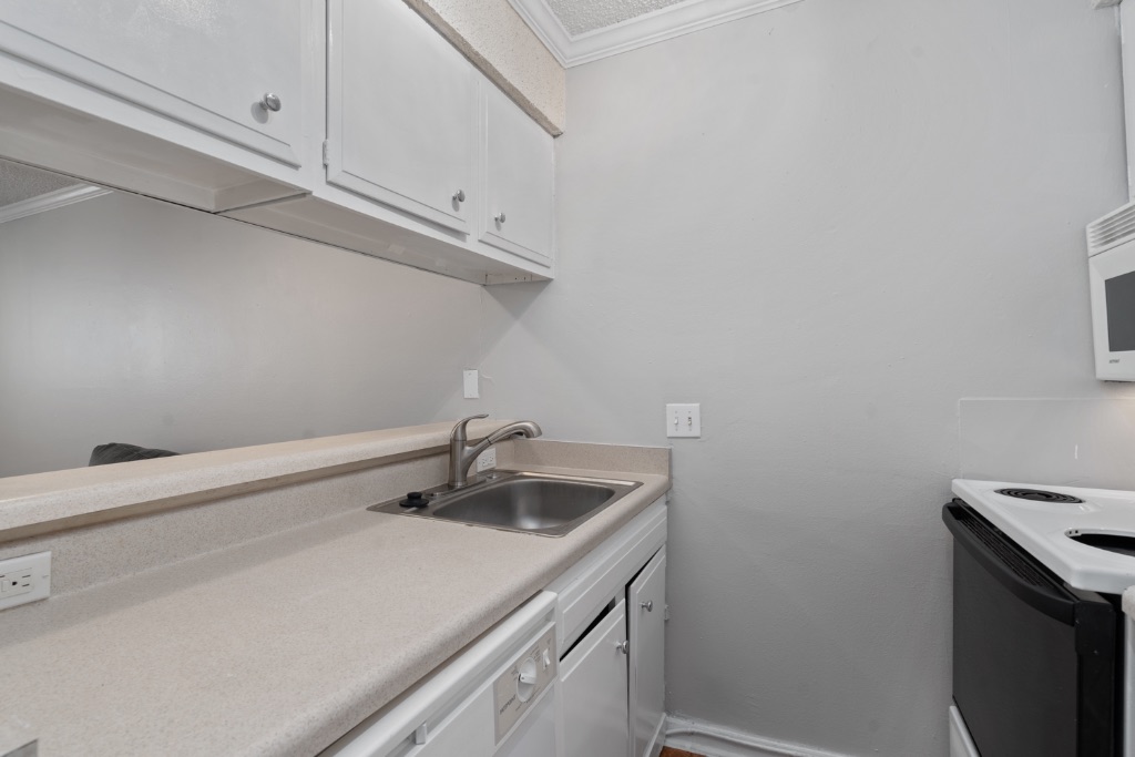 4103 Speedway, Unit 105 Austin, TX 78751 - Photo 2 of 10 Kitchen with white cabinets, white appliances, crown molding, and light countertops