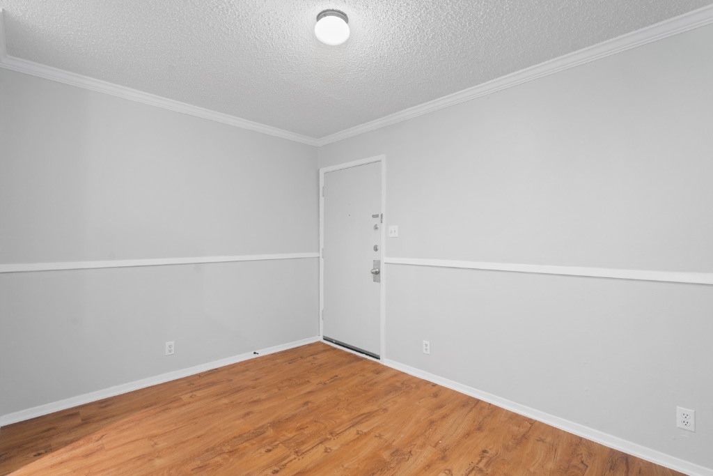 4103 Speedway, Unit 105 Austin, TX 78751 - Photo 3 of 10 Spare room featuring a textured ceiling, crown molding, and wood finished floors