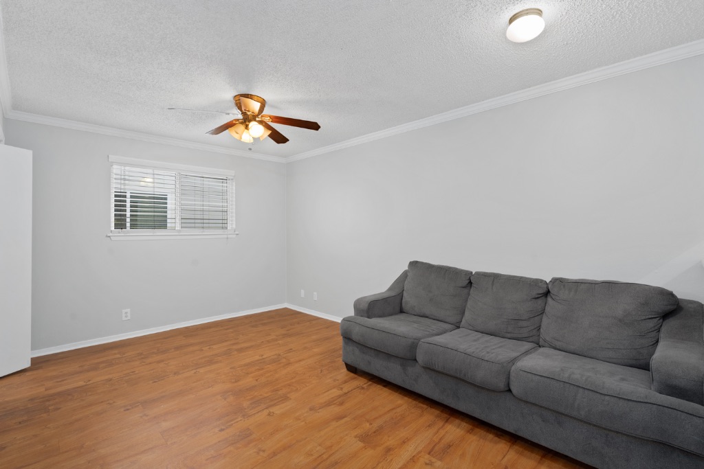 4103 Speedway, Unit 105 Austin, TX 78751 - Photo 5 of 10 Living area featuring crown molding, a textured ceiling, light wood finished floors, and a ceiling fan