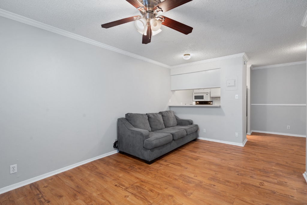 4103 Speedway, Unit 105 Austin, TX 78751 - Photo 6 of 10 Unfurnished living room featuring a textured ceiling, crown molding, light wood finished floors, and ceiling fan