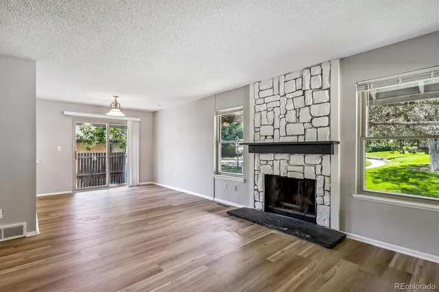 a view of an empty room with wooden floor fireplace and a window