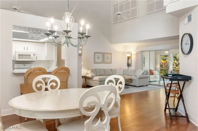 a living room with couches chandelier and a dining table with wooden floor