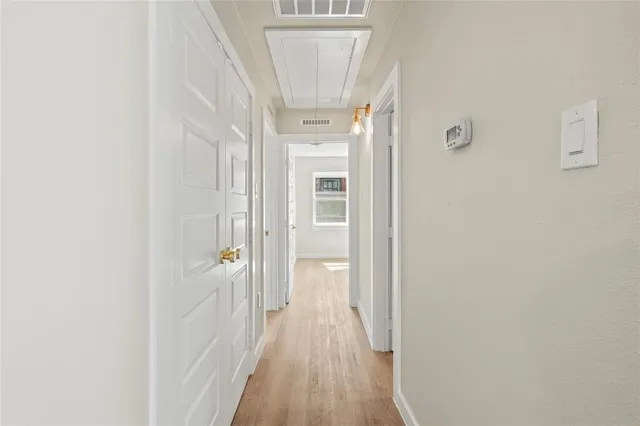 a view of a hallway with wooden floor and a bathroom