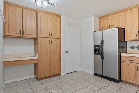a view of a refrigerator in kitchen and white cabinets