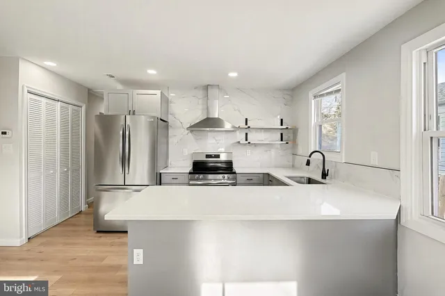 a kitchen with stainless steel appliances granite countertop a sink a stove a refrigerator a washer dryer and white cabinets