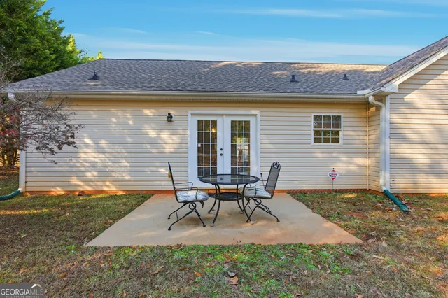 a patio with table and chairs and potted plants