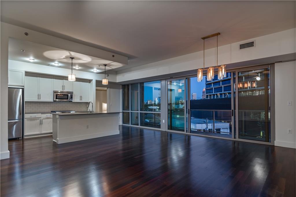 a open kitchen with stainless steel appliances granite countertop a refrigerator a sink a stove and oven a wooden floors