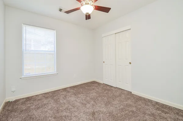 an empty room with a window and a fan