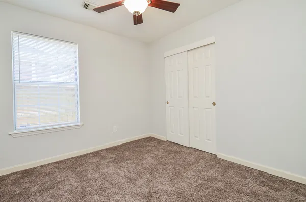 an empty room with a window and a fan