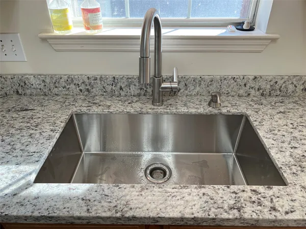 a kitchen with granite countertop wood cabinets stainless steel appliances and a sink