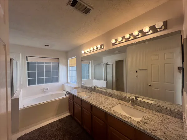 a bathroom with a granite countertop sink a large mirror and a shower