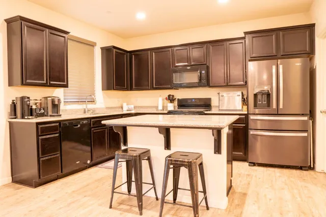 a kitchen with stainless steel appliances kitchen island granite countertop a refrigerator and a stove top oven