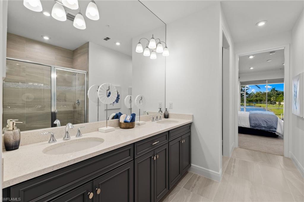 4558 Arboretum Circle, Unit 104 Naples, FL 34112 - Photo 14 of 19 a en suite bathroom with a double vanity sink and a mirror