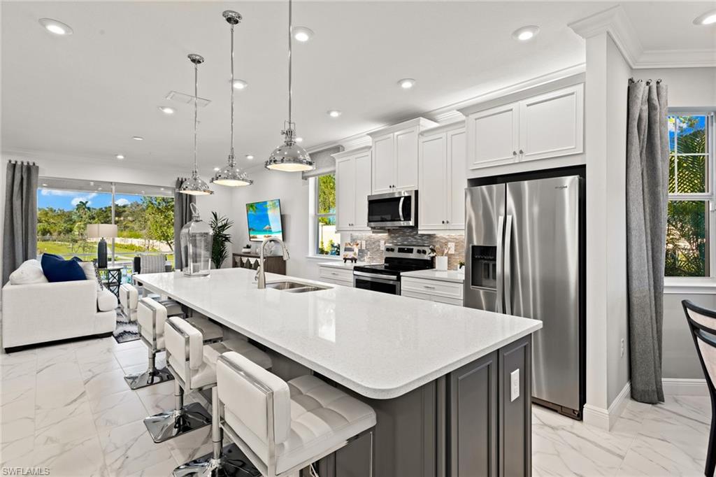 4558 Arboretum Circle, Unit 104 Naples, FL 34112 - Photo 7 of 19 a kitchen with stainless steel appliances a table chairs refrigerator and microwave