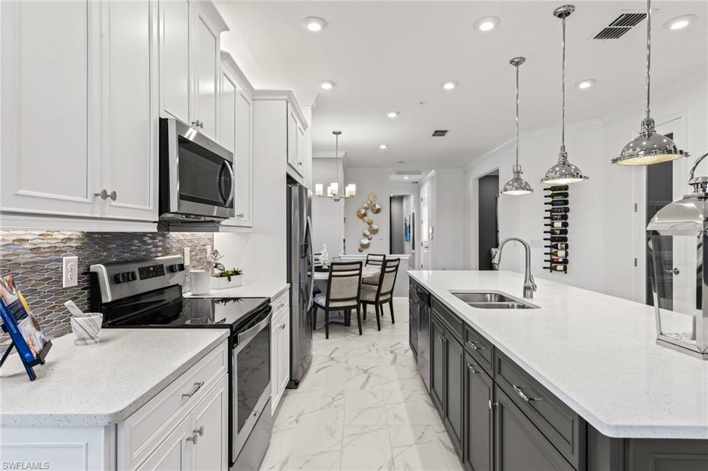4558 Arboretum Circle, Unit 104 Naples, FL 34112 - Photo 8 of 19 a kitchen with kitchen island granite countertop a sink a counter top space appliances and cabinets