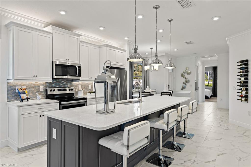 4558 Arboretum Circle, Unit 104 Naples, FL 34112 - Photo 9 of 19 a kitchen with stainless steel appliances kitchen island granite countertop a sink a stove a refrigerator and a dining table with wooden floor
