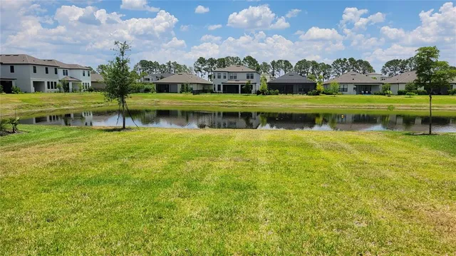 a view of residential houses with yard and lake view