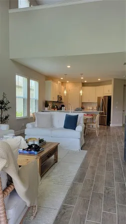 a living room with couches and kitchen view with wooden floor