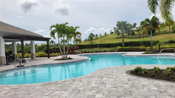 a view of a swimming pool and lounge chairs in back yard of a house