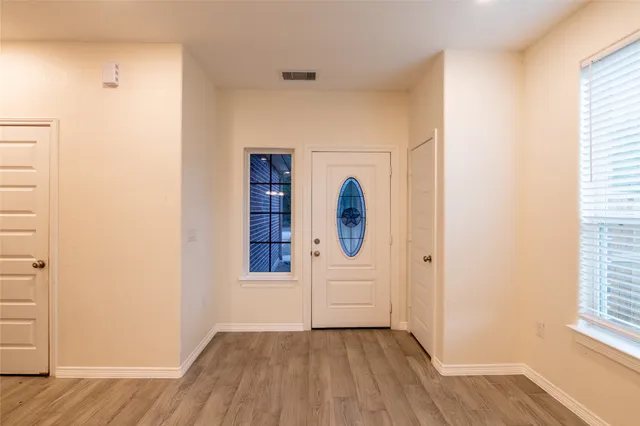 a view of a hallway with wooden floor and cabinet