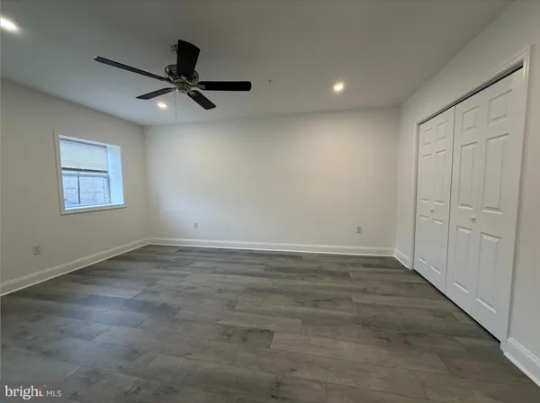 an empty room with a ceiling fan and windows