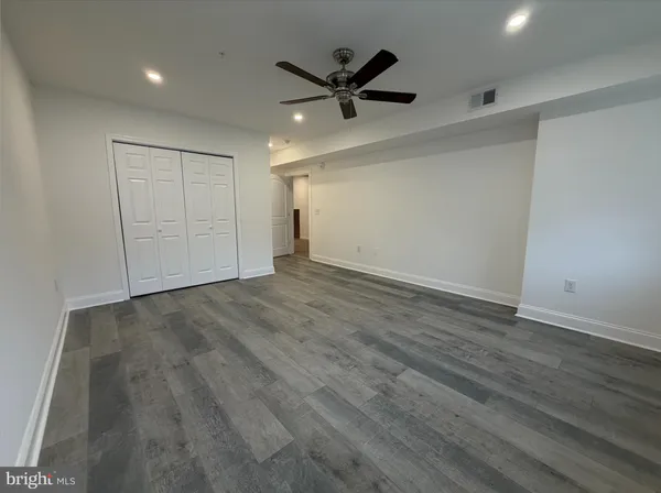 an empty room with wooden floor and a ceiling fan