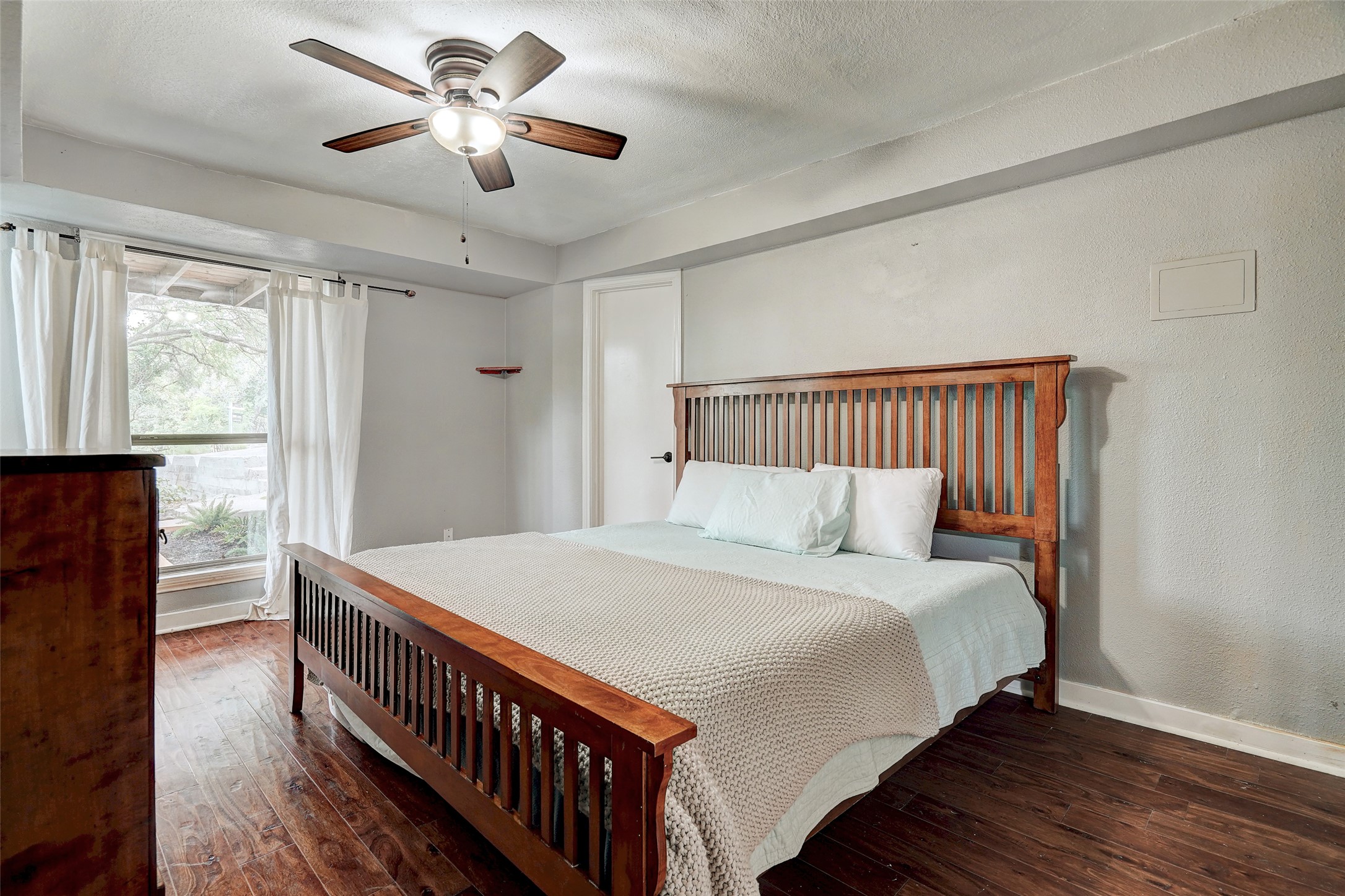 8804 Mountain Ridge Drive, Unit B Austin, TX 78759 - Photo 11 of 17 Well-lit sleeping quarters with a ceiling fan, wood floors, and views of the garden through large windows.