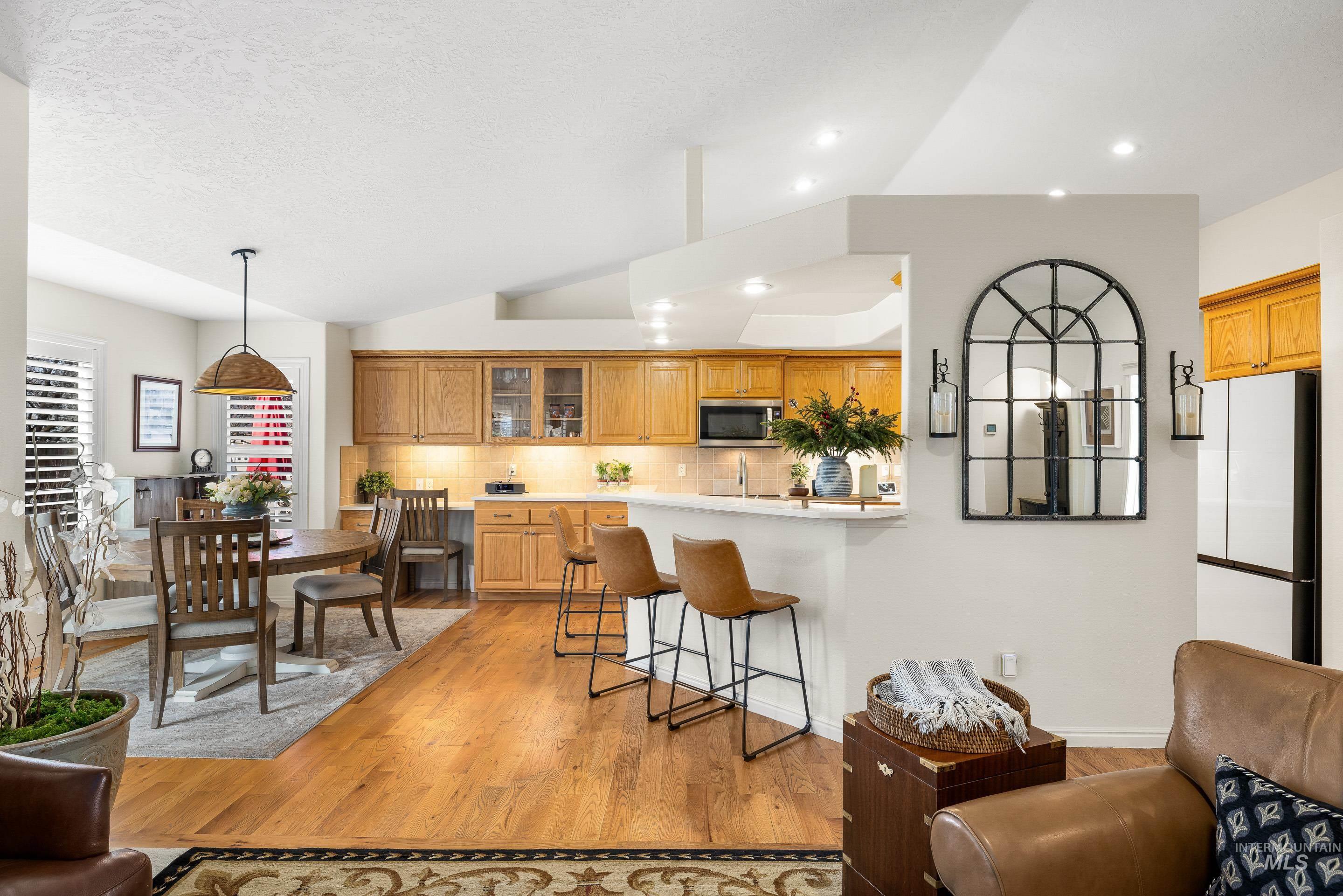 3631 North Alexis Way Meridian, ID 83646 - Photo 13 of 49 Kitchen featuring a breakfast bar, light wood-style floors, decorative backsplash, light countertops, and glass insert cabinets