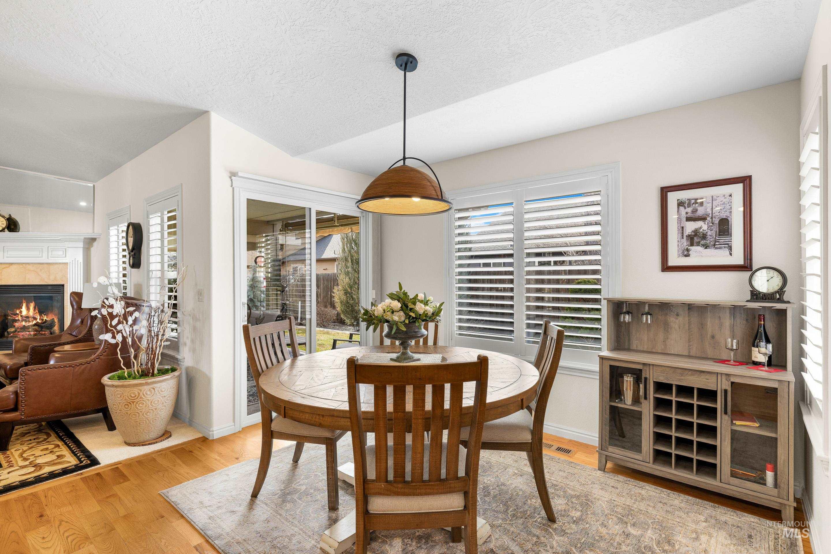 3631 North Alexis Way Meridian, ID 83646 - Photo 16 of 49 Dining room featuring a fireplace, light wood-style flooring, and a textured ceiling