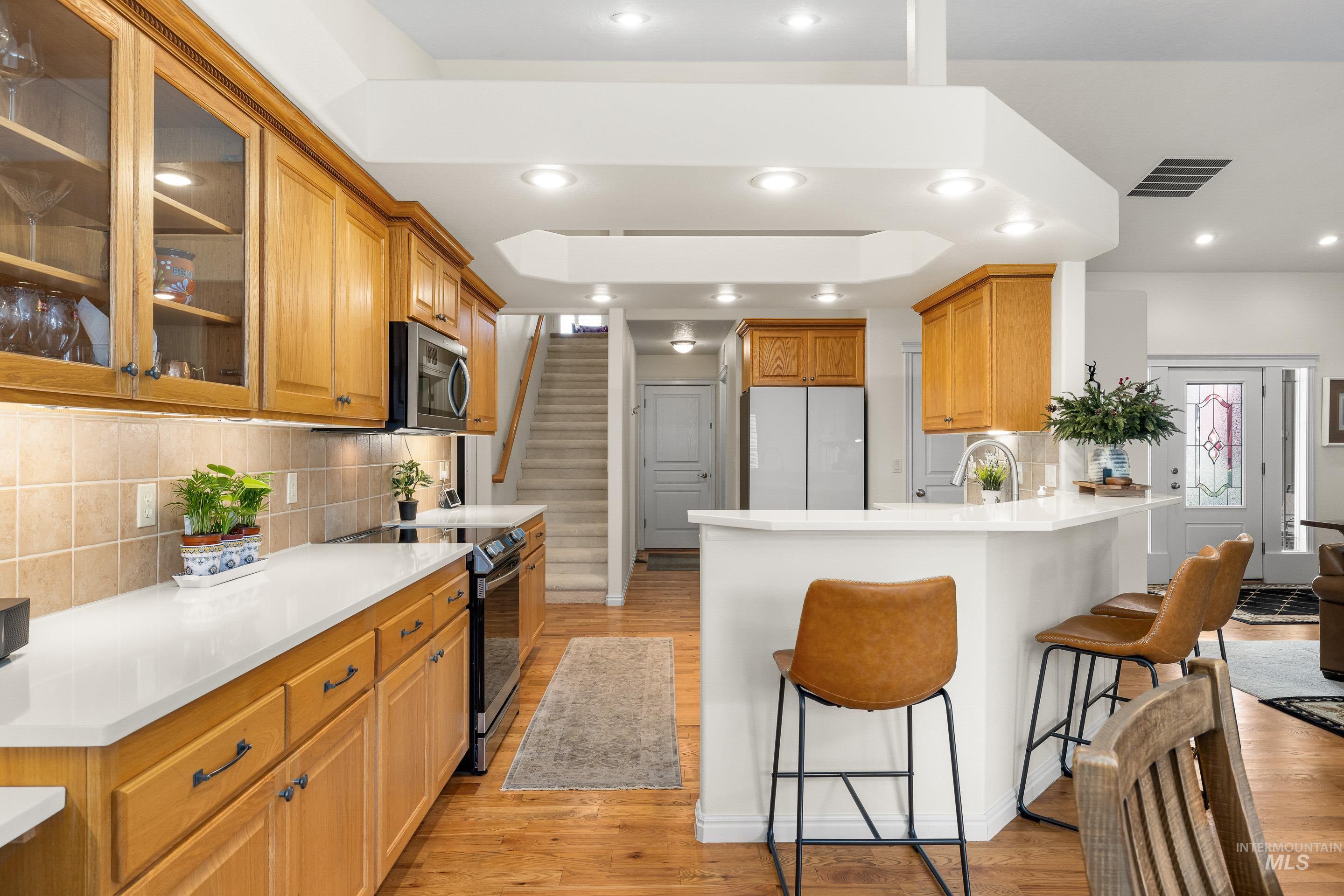 3631 North Alexis Way Meridian, ID 83646 - Photo 19 of 49 Kitchen with electric range oven, glass insert cabinets, freestanding refrigerator, a breakfast bar, and light wood-type flooring