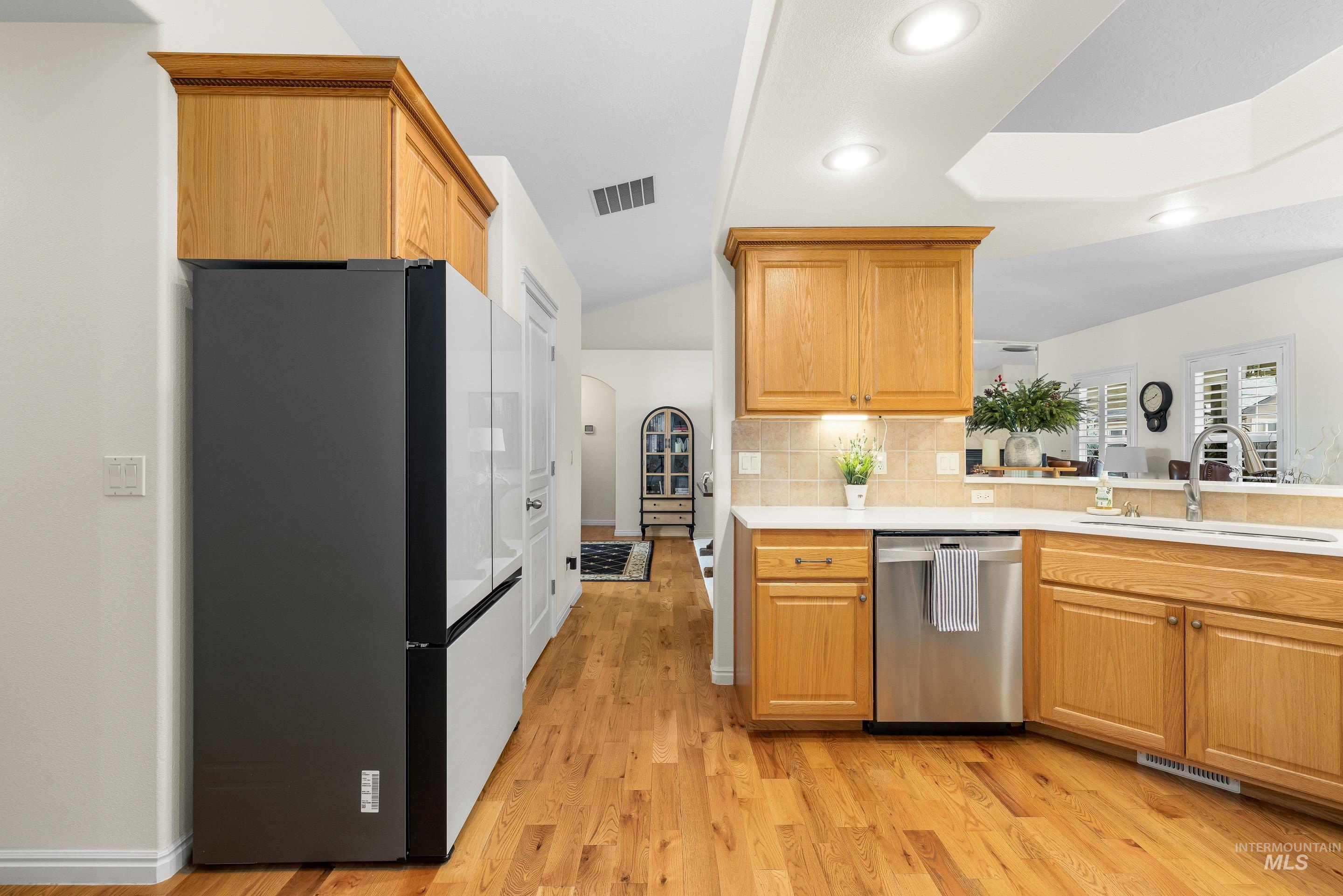 3631 North Alexis Way Meridian, ID 83646 - Photo 21 of 49 Kitchen with freestanding refrigerator, dishwasher, arched walkways, light wood-style flooring, and tasteful backsplash