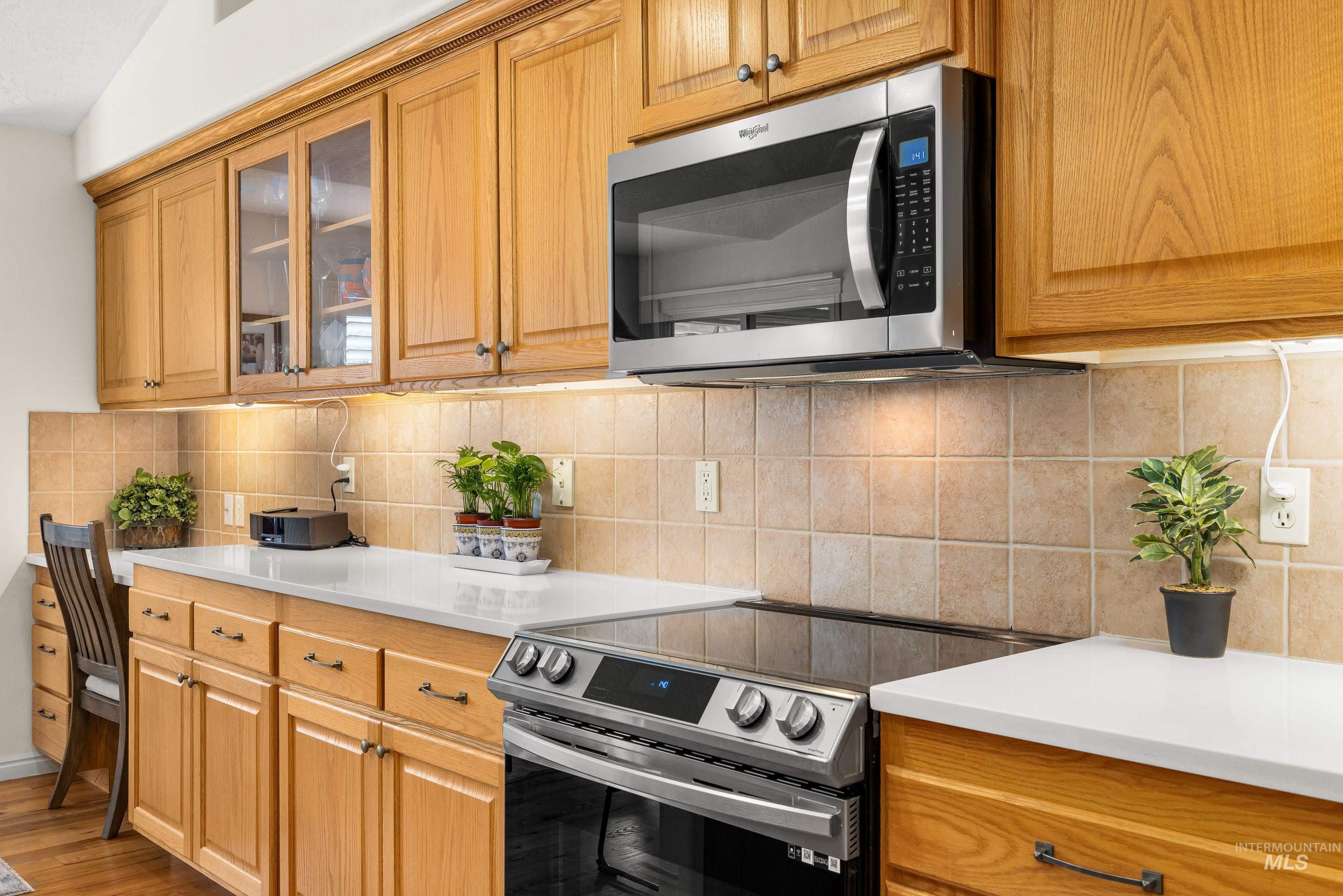 3631 North Alexis Way Meridian, ID 83646 - Photo 26 of 49 Kitchen featuring appliances with stainless steel finishes, tasteful backsplash, brown cabinets, and glass insert cabinets