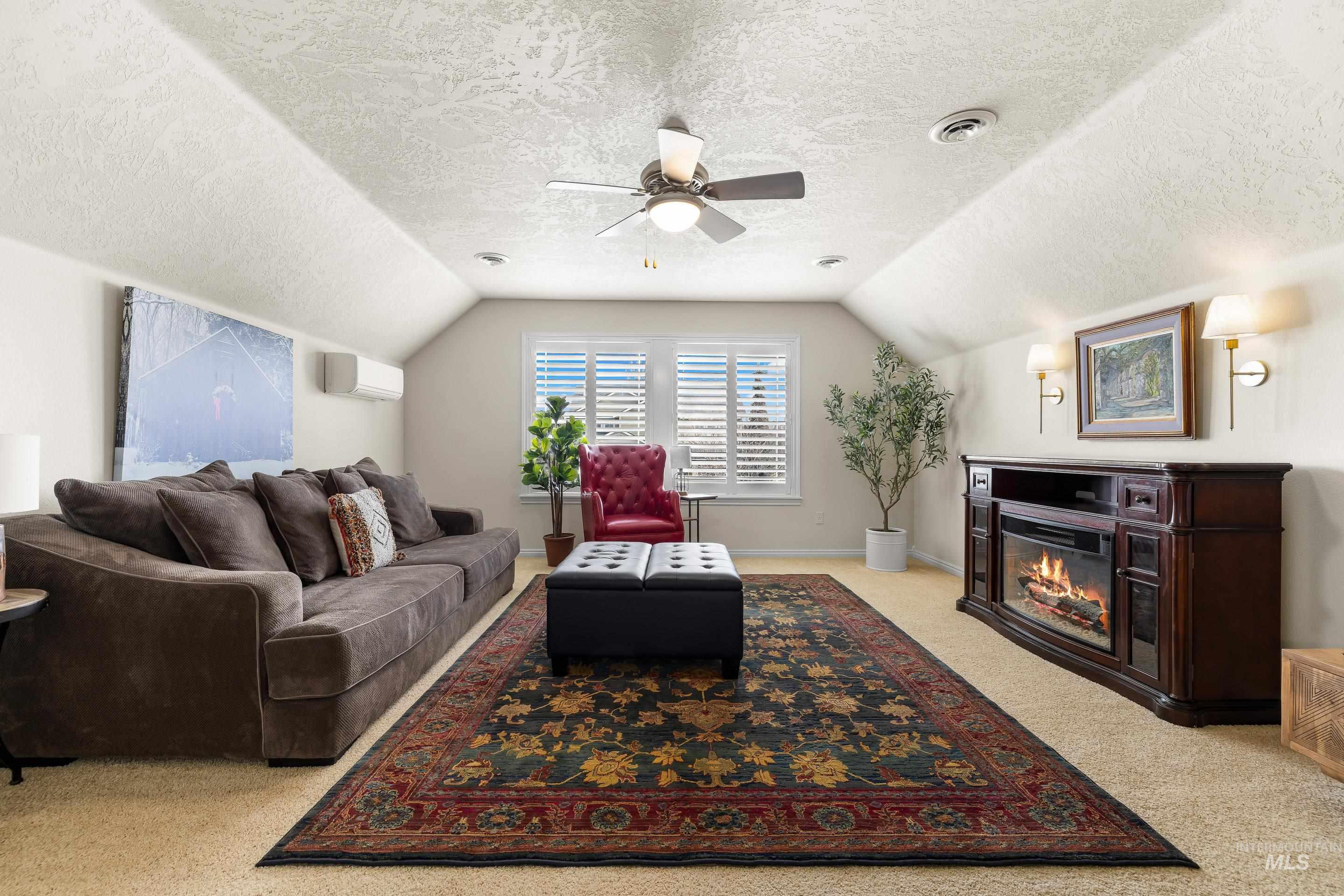 3631 North Alexis Way Meridian, ID 83646 - Photo 38 of 49 Living area with a textured ceiling, lofted ceiling, a glass covered fireplace, ceiling fan, and light colored carpet